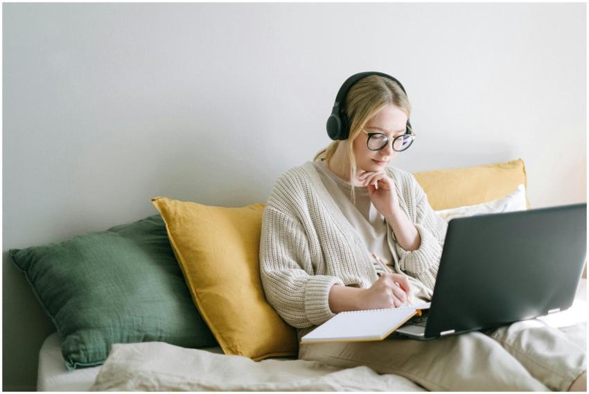 A focused woman in glasses and headphones works on