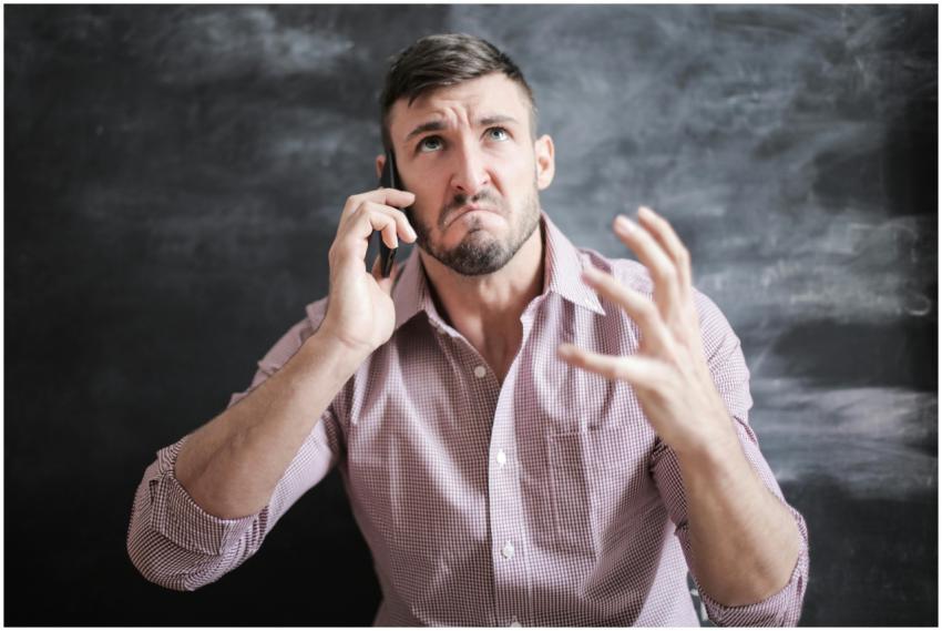 Adult man in pink dress shirt looking stressed whi