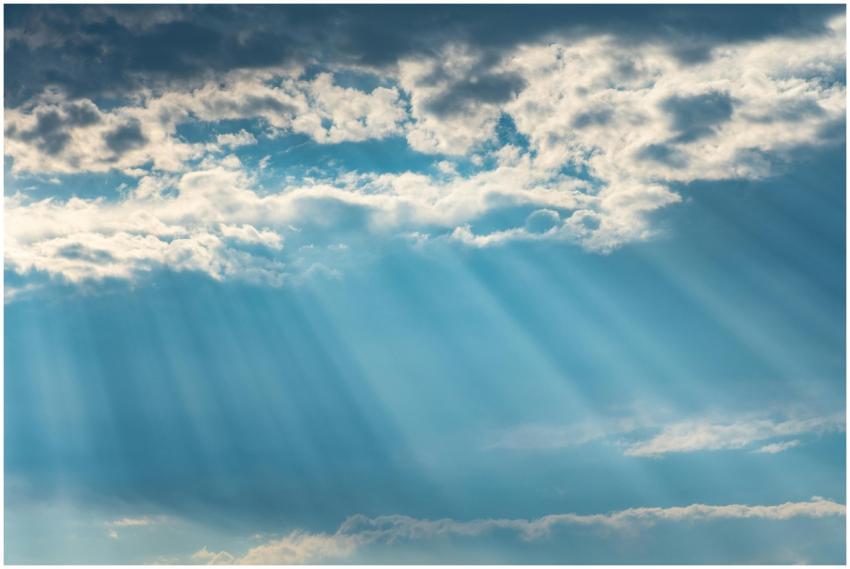 Vibrant sunrays pierce through a cloudy sky, creat