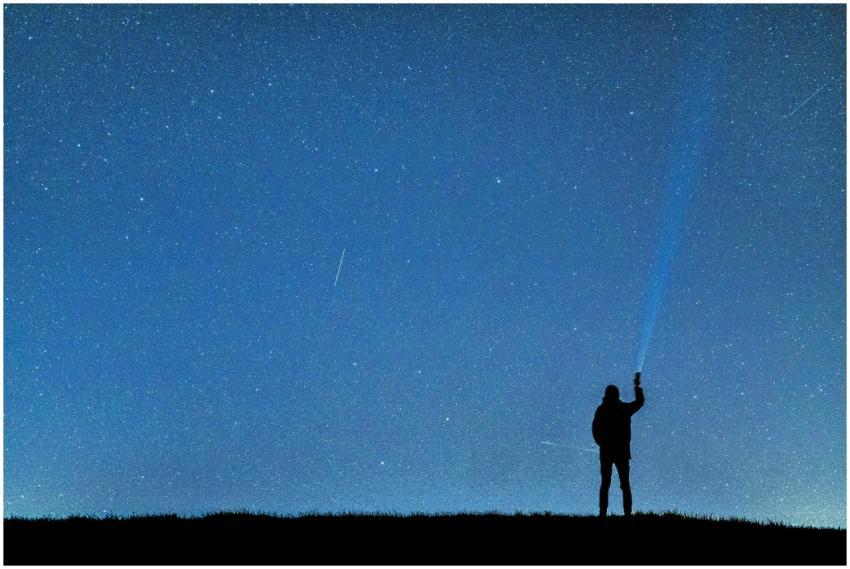 A person with a flashlight gazing at the stars, cr