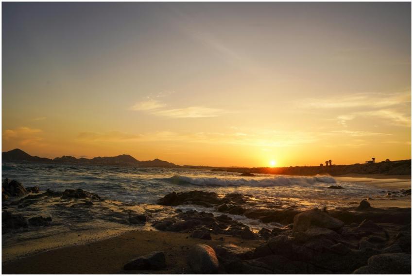 Breathtaking sunset over rocky shoreline, waves cr