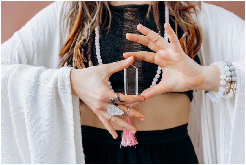 A woman wearing jewelry holds a clear healing crys