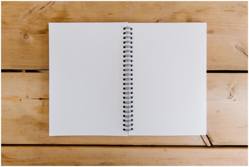 Top view of an open spiral notebook on a wooden de