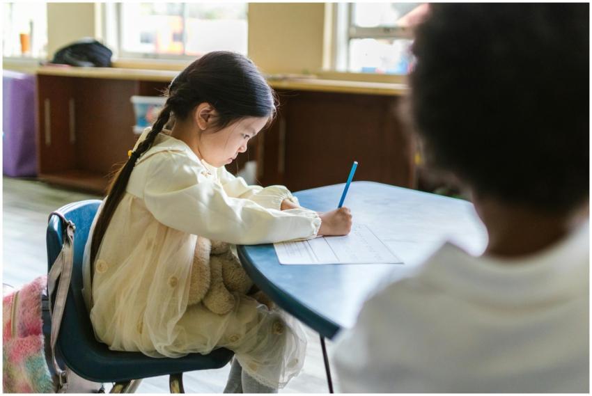 A young child intensely focused on writing at a cl