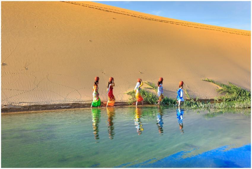 Colorfully dressed women walking by a desert oasis
