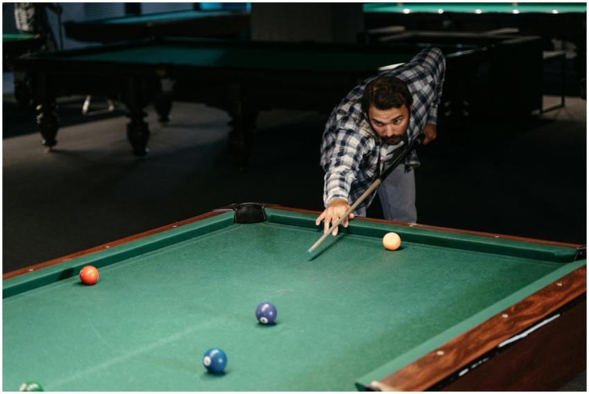 A man focused on making a shot at a billiard table