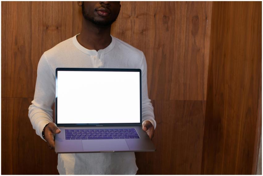 A man holding a laptop with a blank screen, standi