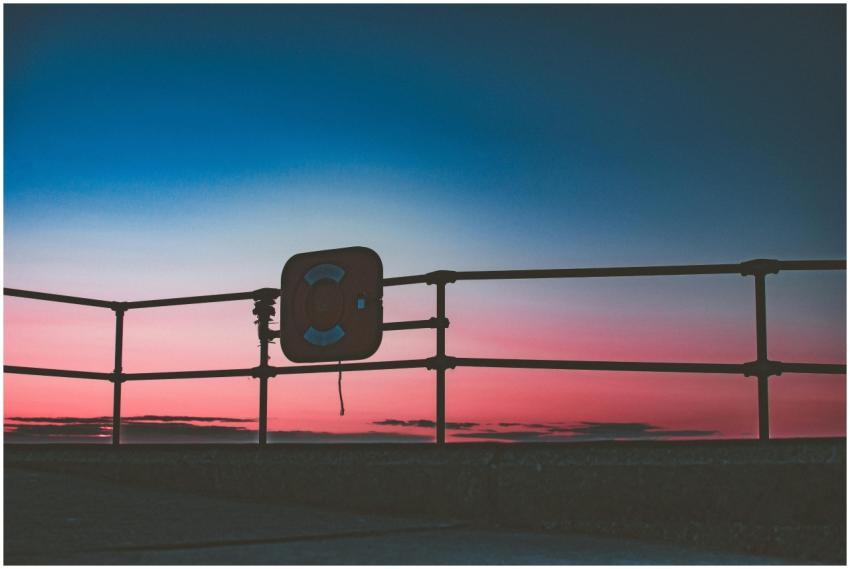 Dramatic sunset at the seaside, featuring railings