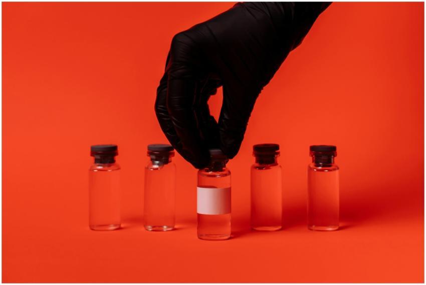 Person wearing black glove grabbing a vaccine vial