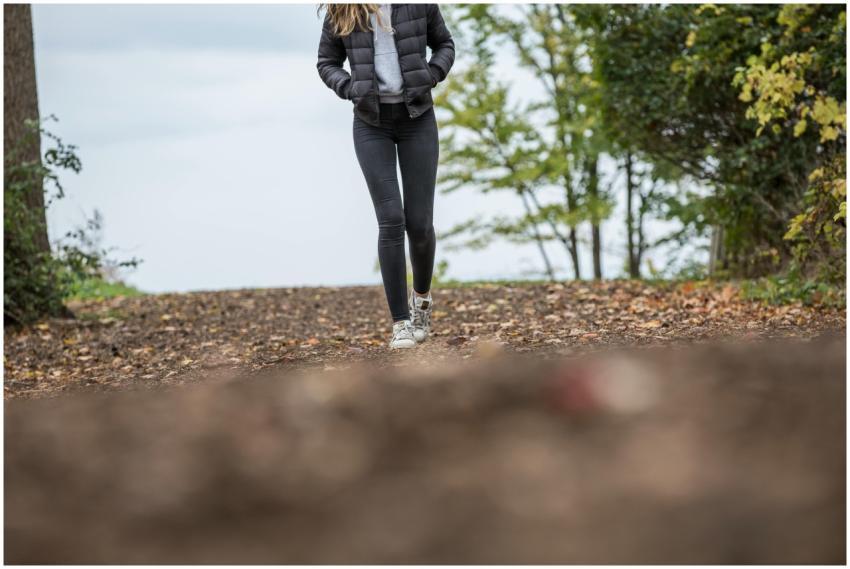 A woman walks along a scenic forest trail during a