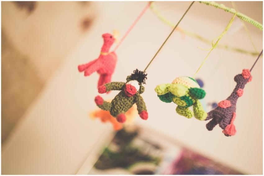 Colorful knitted animal toys hanging from a nurser
