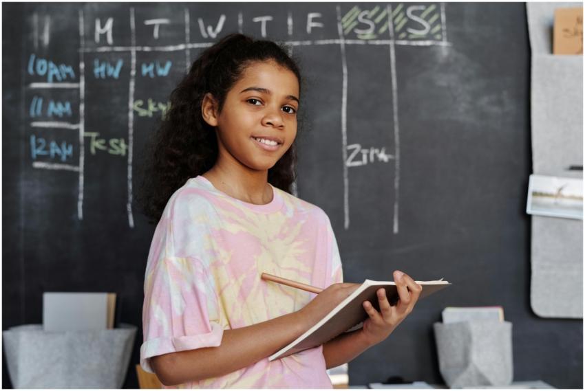 Teenage girl smiling while holding a notebook in a
