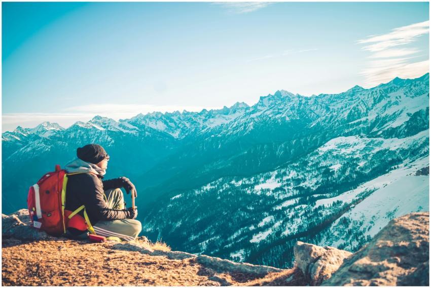 A lone backpacker sitting on a mountain summit adm