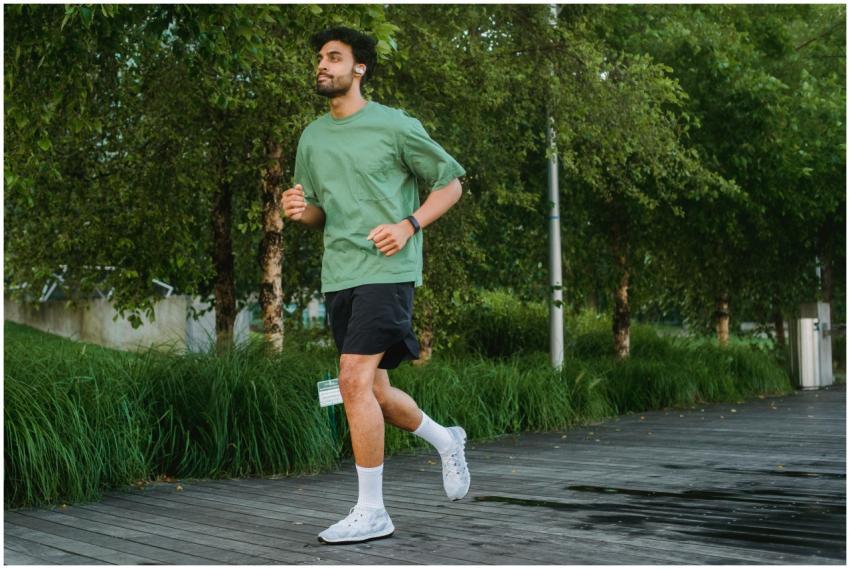 A confident young man jogging in a green park, enj