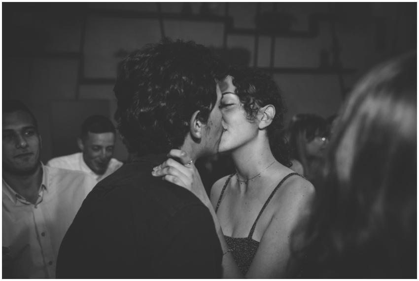 A romantic couple shares a kiss at a lively indoor