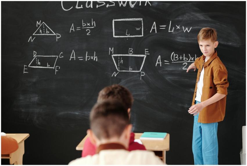 A young student explains math formulas on a blackb