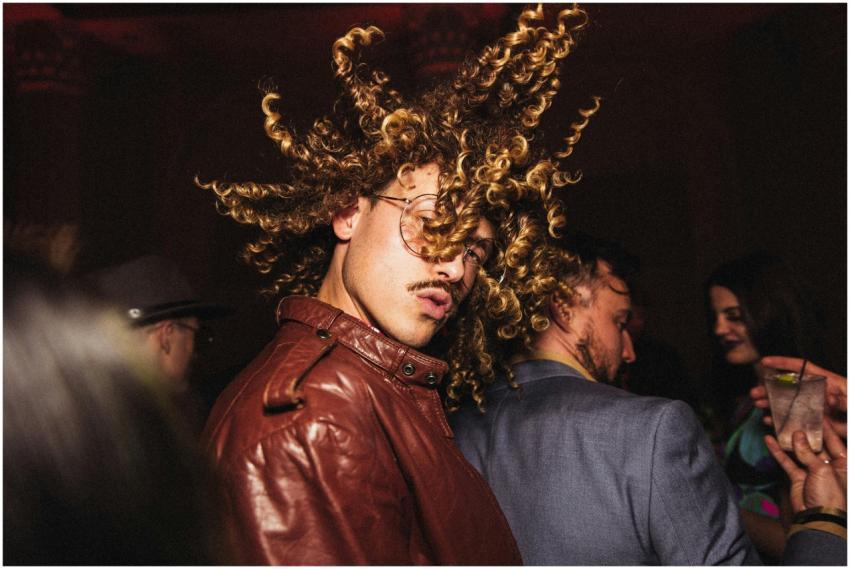 Energetic man with curly hair flips head in lively