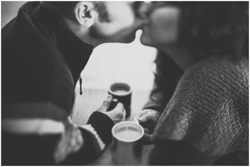 A couple shares a romantic kiss over coffee in a c
