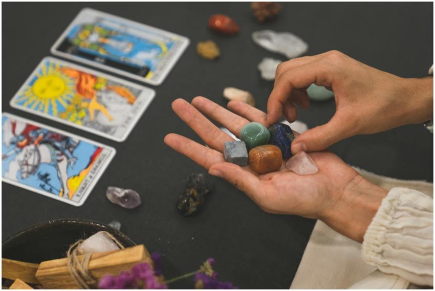 Person holding healing crystals with tarot cards i