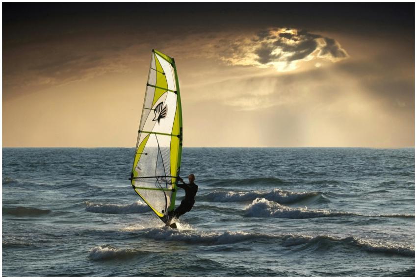 Exciting windsurfing action against a dramatic sun