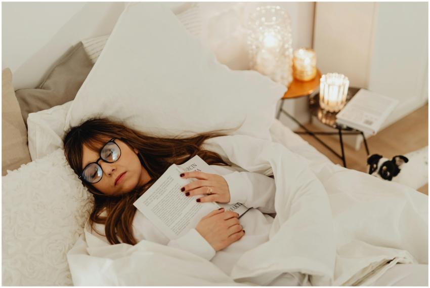 Woman with glasses asleep holding a book in a cozy
