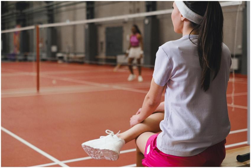 Women enjoying a badminton game indoors. One playe