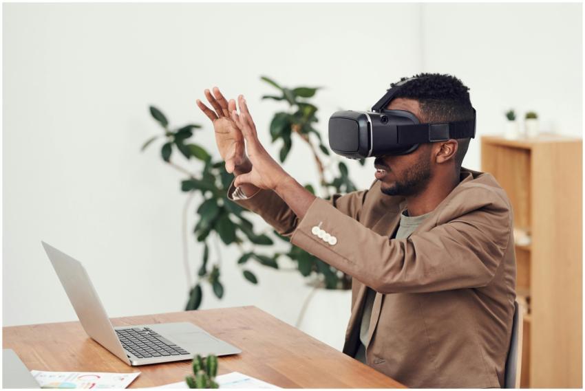 Man using a VR headset in an office with a laptop,