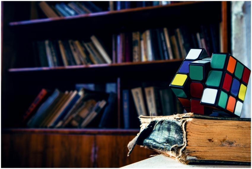 A vivid Rubik's cube resting on a worn book in a c