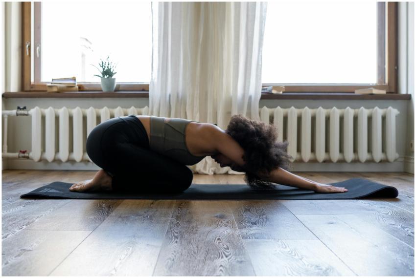 Woman practicing yoga at home on a mat in a cozy r