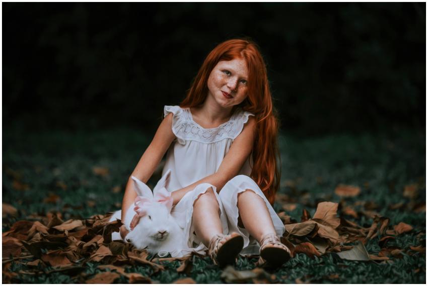 A red-haired girl in a white dress sitting with a