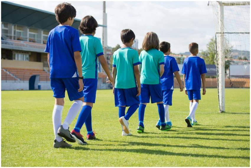 Children in football uniforms walking on a sunny f