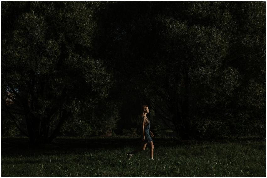 A woman walks through a dark forest, surrounded by