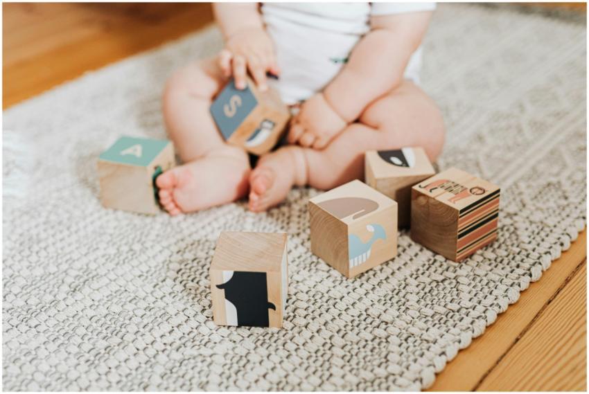 Adorable baby sitting on a rug and playing with co