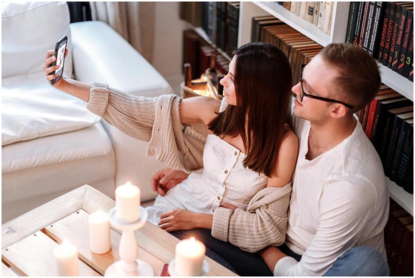 A happy couple taking a selfie indoors, surrounded