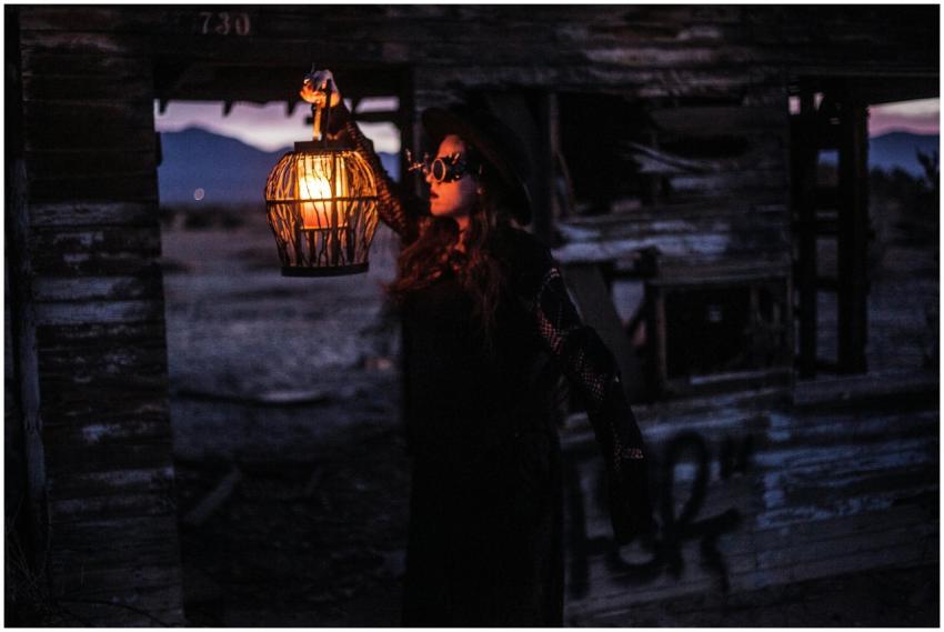 A woman in steampunk attire holds a lantern in a d