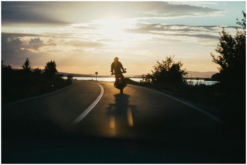 Silhouette of a motorcyclist riding on a scenic ro