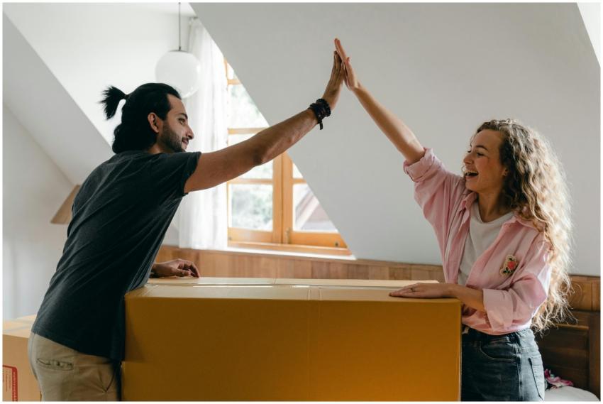 Young couple high-fiving in their new home, happil