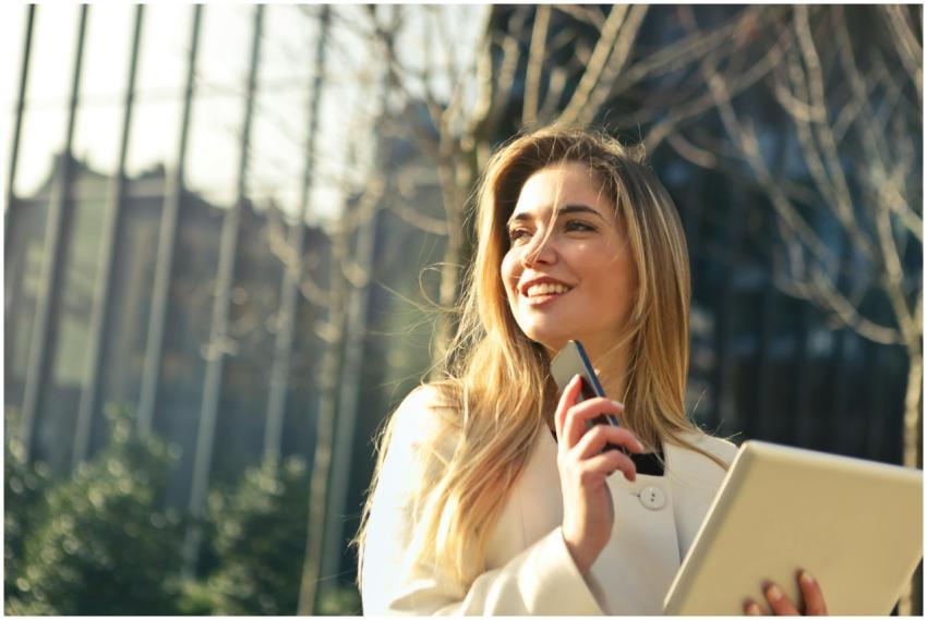 Smiling businesswoman holding smartphone and table