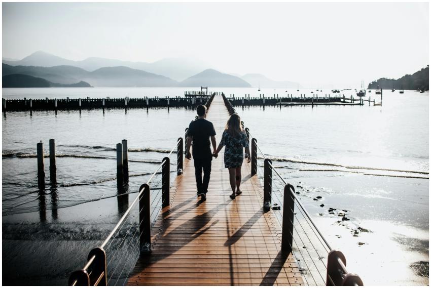 A couple holding hands walking along a pier overlo