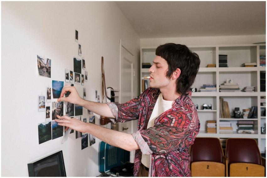Creative young man arranging photographs on a wall