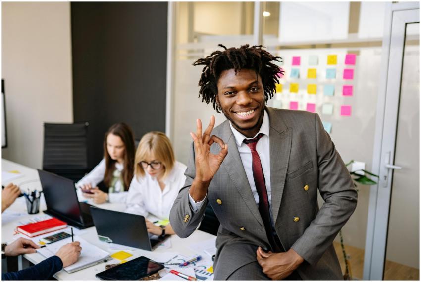 Smiling businessman signaling OK, working with div