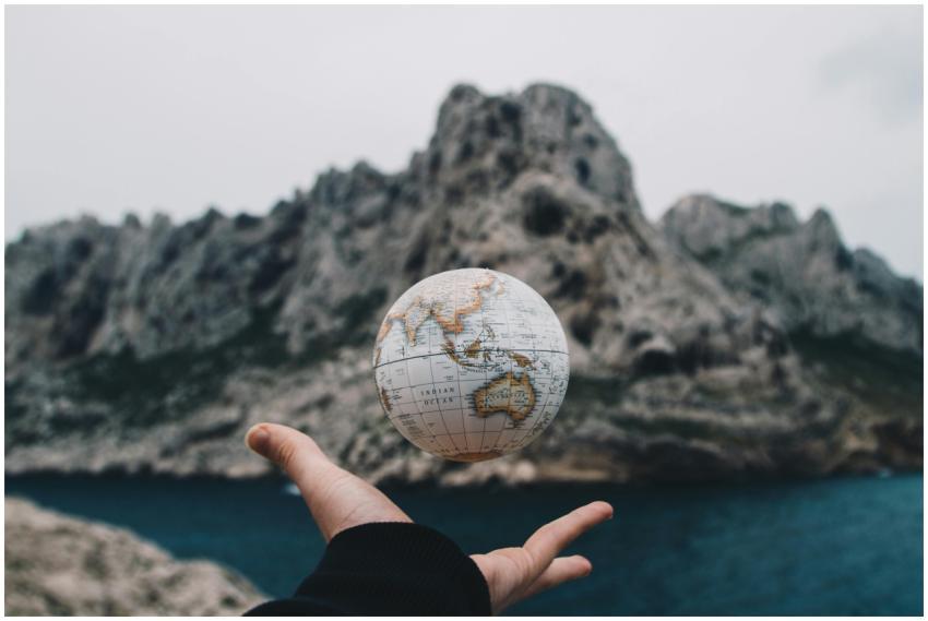 A hand holding a floating globe with a scenic Mars