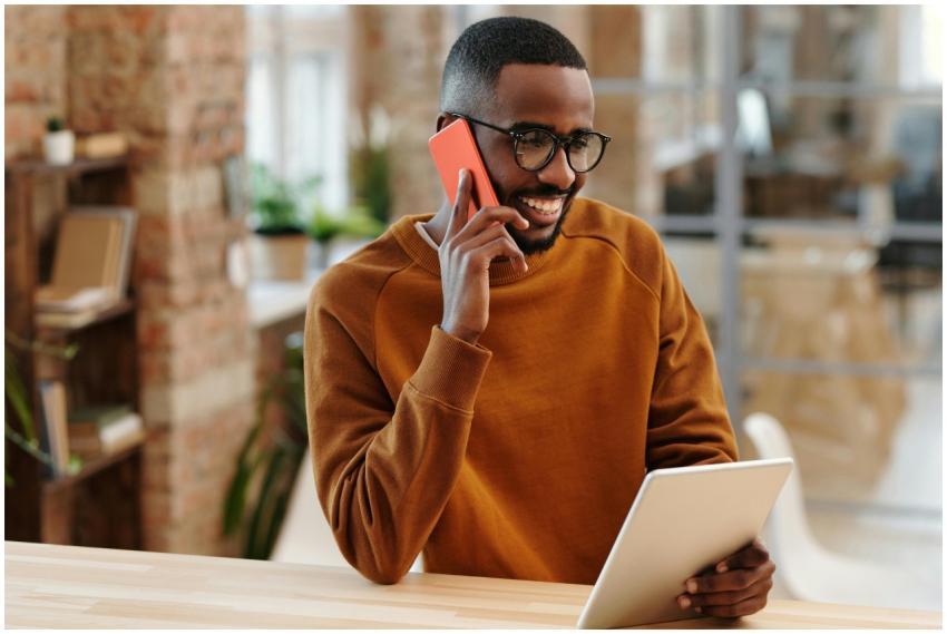 Smiling man in an office multitasking with a phone