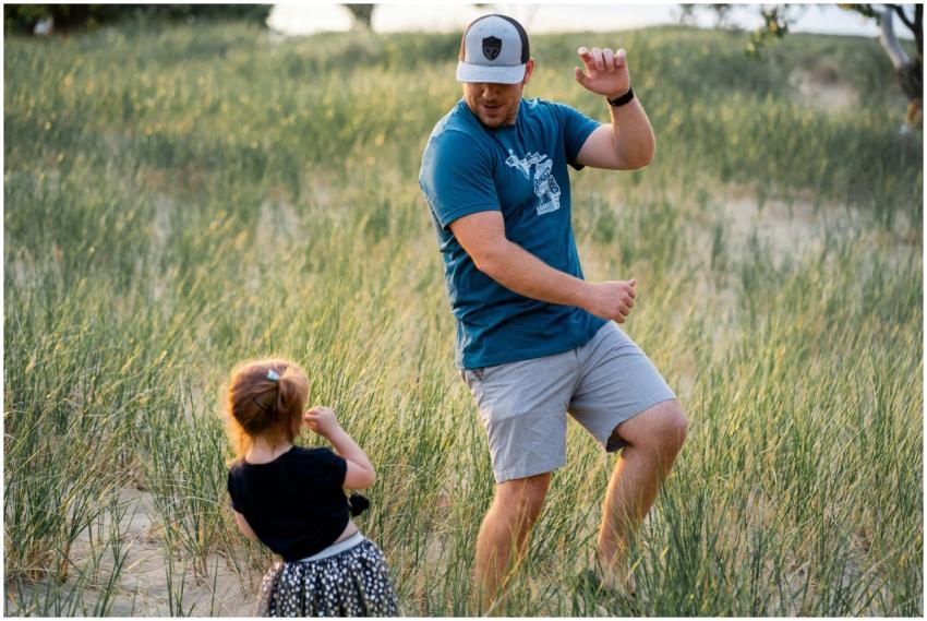 A father dances playfully with his daughter in a s
