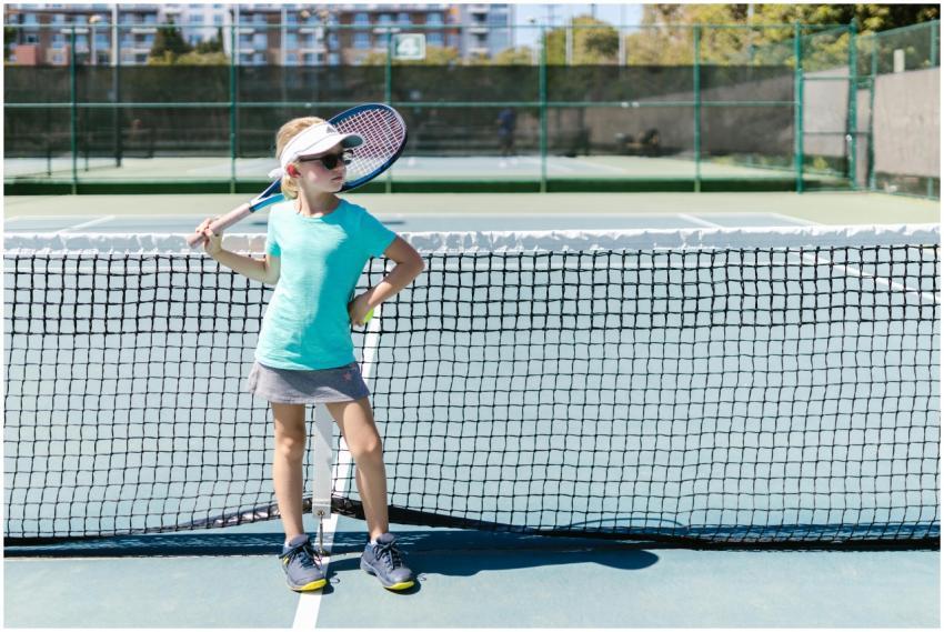 A young girl posing confidently with a tennis rack