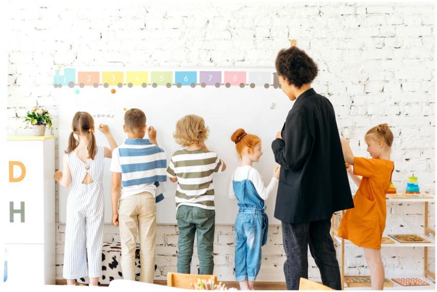 Group of children and teacher interacting with a w