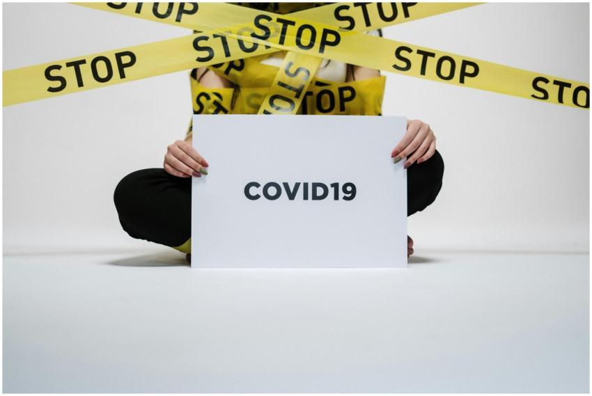 Person holding COVID-19 sign surrounded by yellow