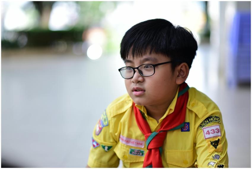 A young scout wearing a yellow uniform with badges