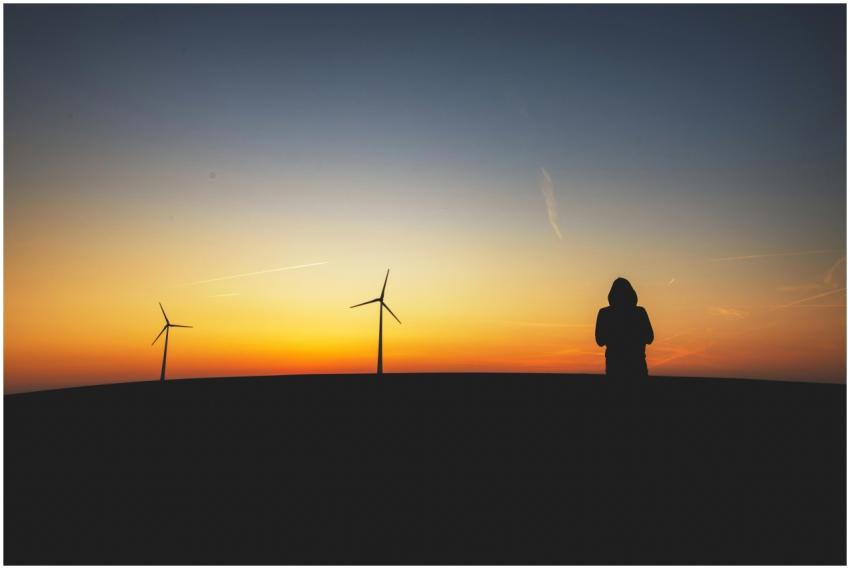 Silhouette of a person and wind turbines against a