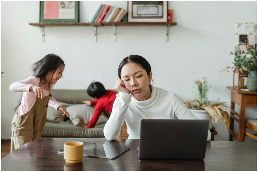 A tired mother working remotely on her laptop whil